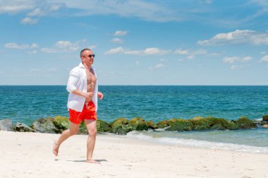 Kumsalda koşan atletik adam. Okyanus sahilde koşu sağlıklı genç atlet