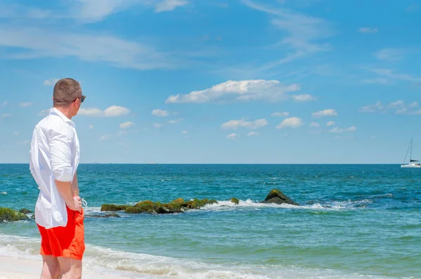 Bărbatul Frumos Stă Plajă Frumoasă Pantaloni Scurți Cămașă Albă — Fotografie, imagine de stoc