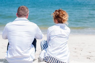 Seven çift tropik sahilde kutlu olsun. Kadın ve deniz kenarında oturan adam