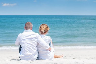 Seven çift tropik sahilde kutlu olsun. Kadın ve deniz kenarında oturan adam