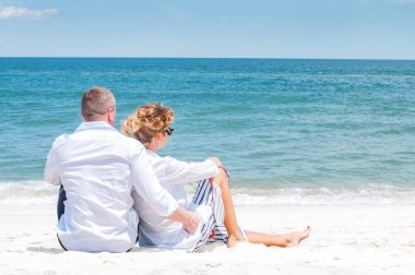 Seven çift tropik sahilde kutlu olsun. Kadın ve deniz kenarında oturan adam