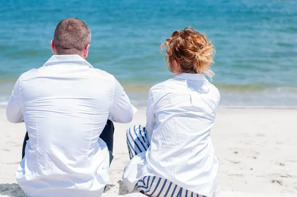 Seven çift tropik sahilde kutlu olsun. Kadın ve deniz kenarında oturan adam