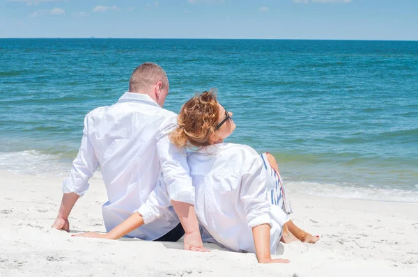 Seven çift tropik sahilde kutlu olsun. Kadın ve deniz kenarında oturan adam