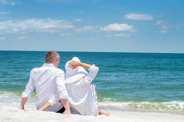 Seven çift tropik sahilde kutlu olsun. Kadın ve deniz kenarında oturan adam