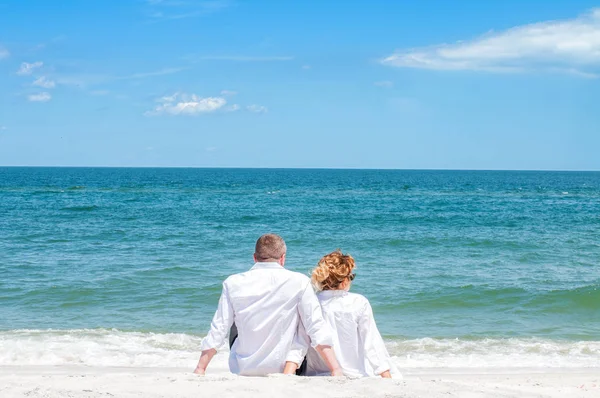 Seven çift tropik sahilde kutlu olsun. Kadın ve deniz kenarında oturan adam