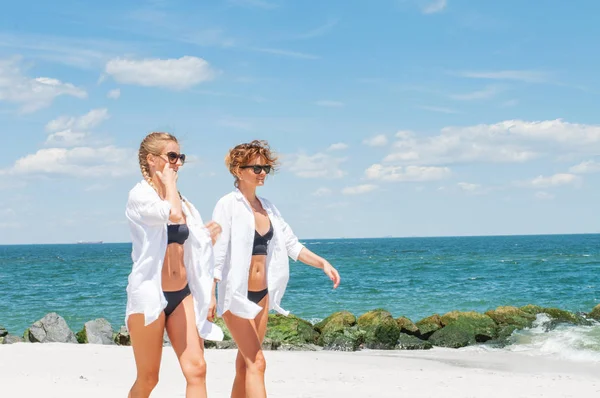 Mutluluk anı. Sahilde bikinili iki çekici kadın. Arkadaşlarım sahilde tatil yaz yürüme. 