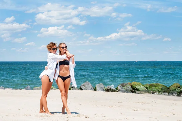 Mutluluk anı. Sahilde bikinili iki çekici kadın. En iyi arkadaşlar eğlenmeye, yaz tatil tatil yaşam tarzı. 