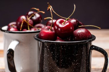 Taze olgun kiraz. Kiraz ahşap masa üzerinde emaye Kupası 