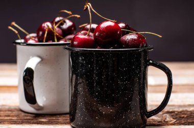 Taze olgun kiraz. Kiraz ahşap masa üzerinde emaye Kupası 