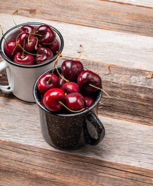 Taze olgun kiraz. Kiraz ahşap masa üzerinde emaye Kupası 