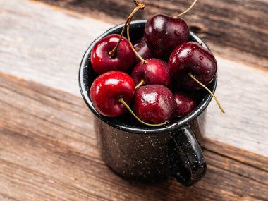 Taze olgun kiraz. Kiraz ahşap masa üzerinde emaye Kupası 