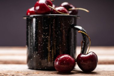 Taze olgun kiraz. Kiraz ahşap masa üzerinde emaye Kupası 