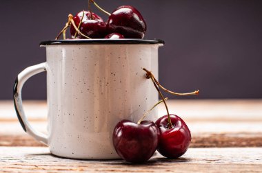 Taze olgun kiraz. Kiraz ahşap masa üzerinde emaye Kupası 