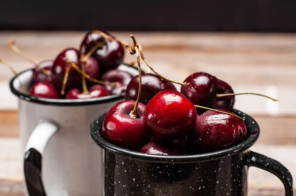 Taze olgun kiraz. Kiraz ahşap masa üzerinde emaye Kupası 