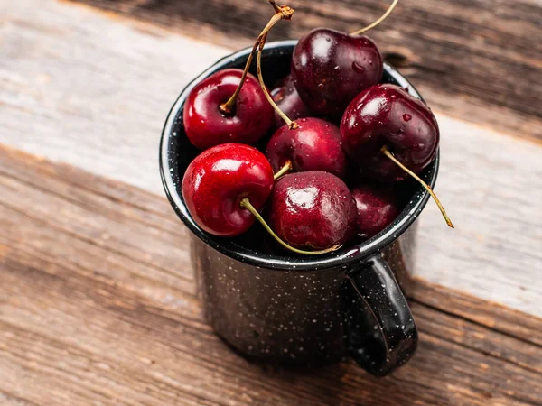 Taze olgun kiraz. Kiraz ahşap masa üzerinde emaye Kupası 