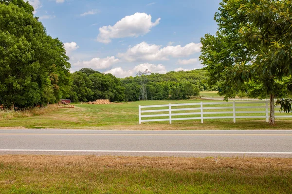 Fence along a farm road in countryside. Country road along the horse farms