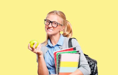 Mutlu genç öğrenci kız kitap, lise ya da üniversite graduand sarı arka plan üzerinde tutarak. Okula dönüş