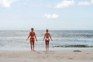 Mutluluk anı. Sahilde bikinili iki çekici kadın. En iyi arkadaşlar eğlenmeye, yaz tatil tatil yaşam tarzı