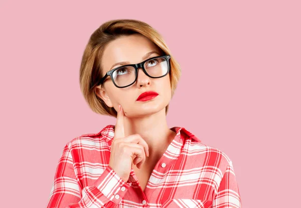 ピンクの背景に見上げる表情に疑問を持つ若い思考ビジネス女性 — ストック写真