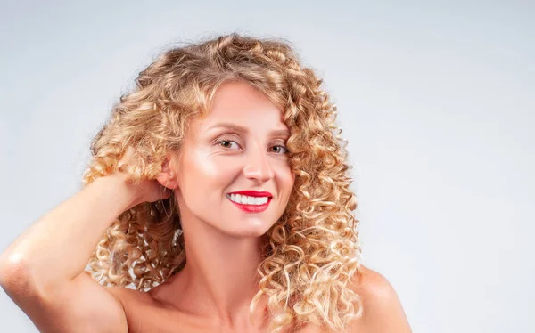 Happy girl with healthy curly hair. Beautiful woman with wavy blonde hair.