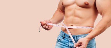 Kusursuz bir beden beline pastel arka plan üzerinde ölçüm ile kas adam. 