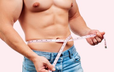 Kusursuz bir beden beline pembe bir arka plan üzerinde ölçüm ile kas adam.