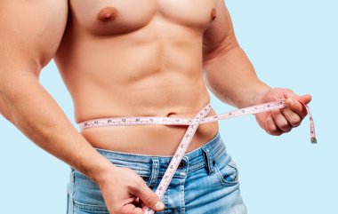 Kusursuz bir beden beline mavi arka plan üzerinde ölçüm ile kas adam.