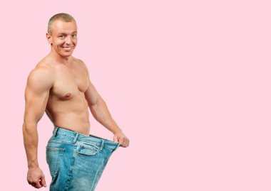 Diyet, kilo kaybı kavramı pembe bir arka plan üzerinde sonra büyük kot giyen adam