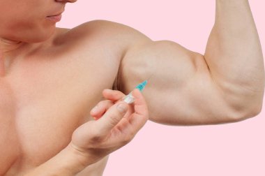 Steroid enjeksiyonu pembe arka plan koluna alarak vücut geliştirmeci. 