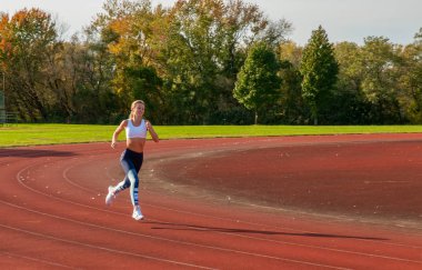 Sağlıklı yaşam tarzı genç fitness kadın çalışan. Kadın atlet atletizm yarış pistinde pratik.