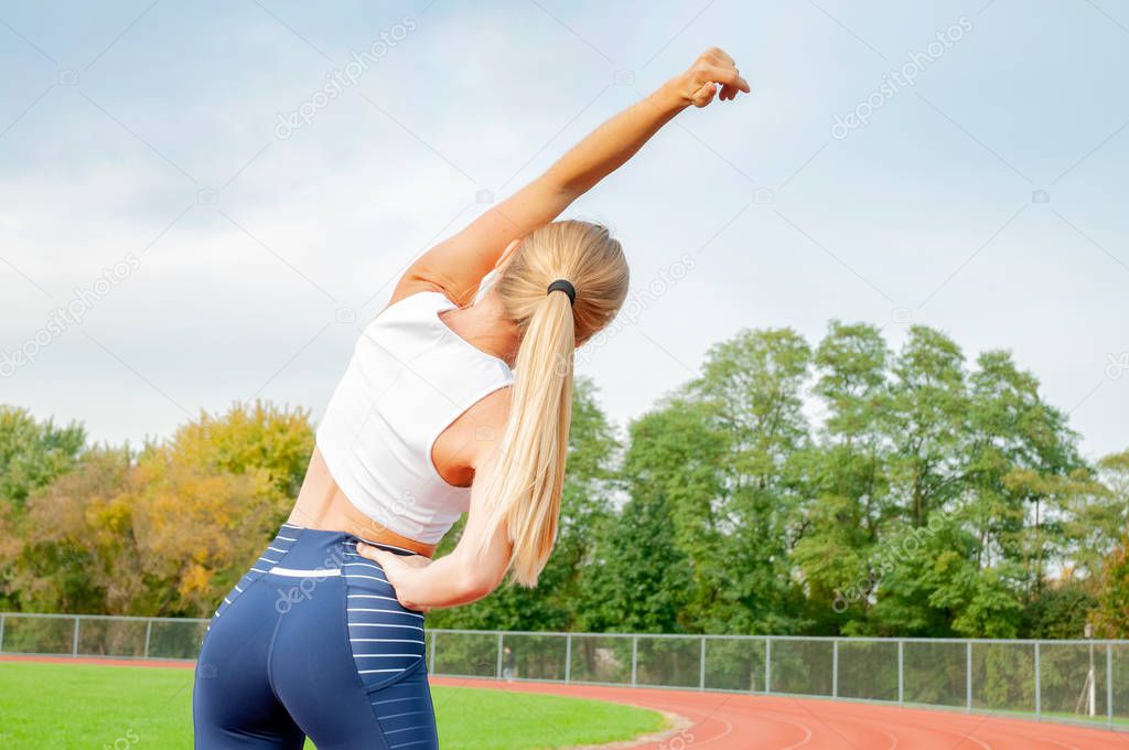 Fitness woman doing warm up exercises. Sport girl doing stretching her arms at outdoors stadium