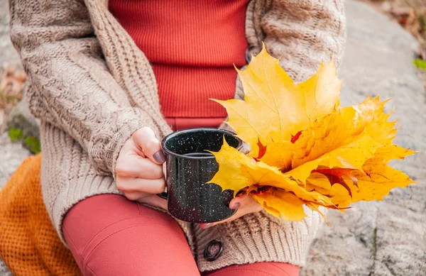 Woman holding mug of coffee in the hands outdoor. Beautiful woman drinking coffee in autumn park.