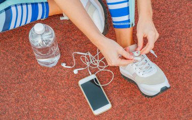 Spor kadın atlet ayakkabı bağcığı bağlama. Kadın bir stadyum koşu parkuru üzerinde spor ayakkabılarını bağlama. Egzersiz kavramı