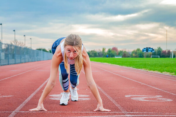 Young fitness woman waiting for start of race on a stadium.