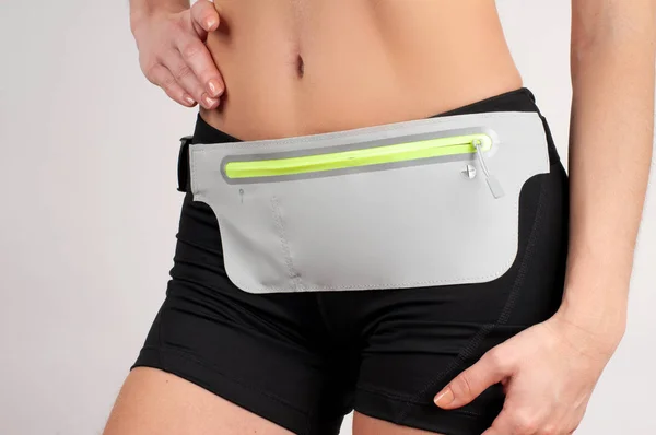 Fitness woman in sport shortwith waist bag for smartphone on white background