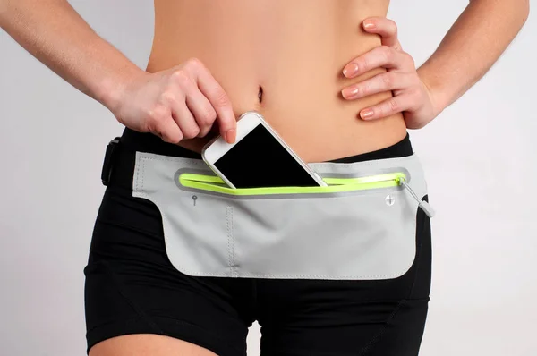 Fitness woman wear waist bag with smartphone inside on white background