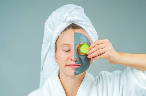 Spa Clay Mask. Beautiful young woman with clay facial mask with cucumbers on eyes. Skincare and beauty Concept.