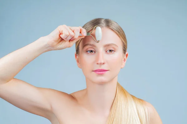 Face massage. Facial beauty treatment. Beautiful woman getting massage face using roller massage