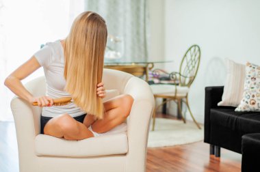 Güzel kız sarışın saçları evde fırça ile penye