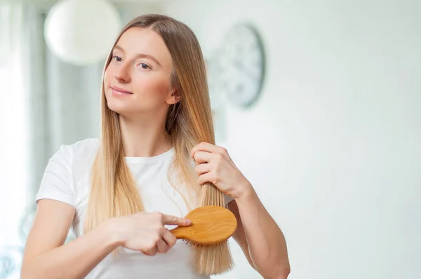 Mooi meisje haar blonde haar met borstel thuis kammen — Stockfoto