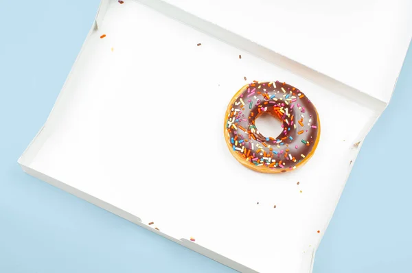 Último donut de chocolate em caixa vazia no fundo azul — Fotografia de Stock