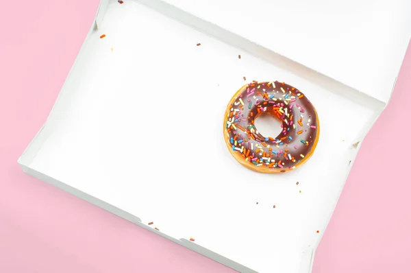 Último donut de chocolate em caixa vazia no fundo rosa — Fotografia de Stock