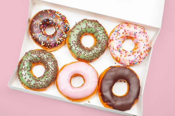 Donuts coloridos em caixa no fundo rosa — Fotografia de Stock