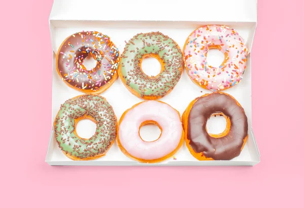 Donuts coloridos em caixa no fundo rosa — Fotografia de Stock