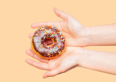 Pastel arka planda renkli donut tutan kadın elleri
