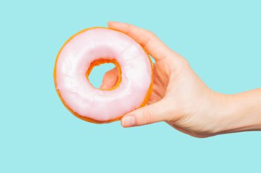 Pastel mavi arka planda renkli donut tutan kadın el