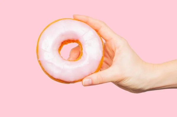 Weibliche Hand hält bunten Donut auf pastellgrünem Hintergrund — Stockfoto
