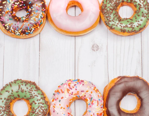 Donuts coloridos sobre fundo de madeira . — Fotografia de Stock