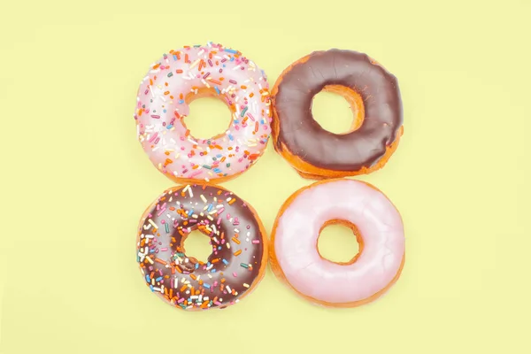 Donuts coloridos sobre fondo amarillo pastel . — Foto de Stock