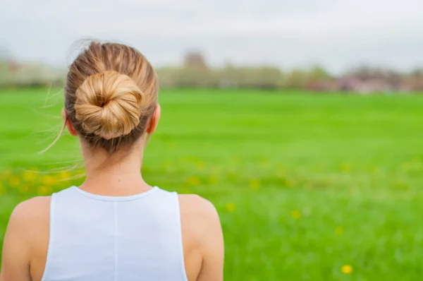 Beautiful young woman is practicing yoga on the grass. View of the back — Stock Photo, Image